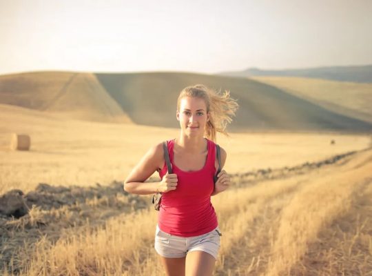 A woman jogging through vast, golden wheat fields under the summer sun, symbolizing freedom and adventure.