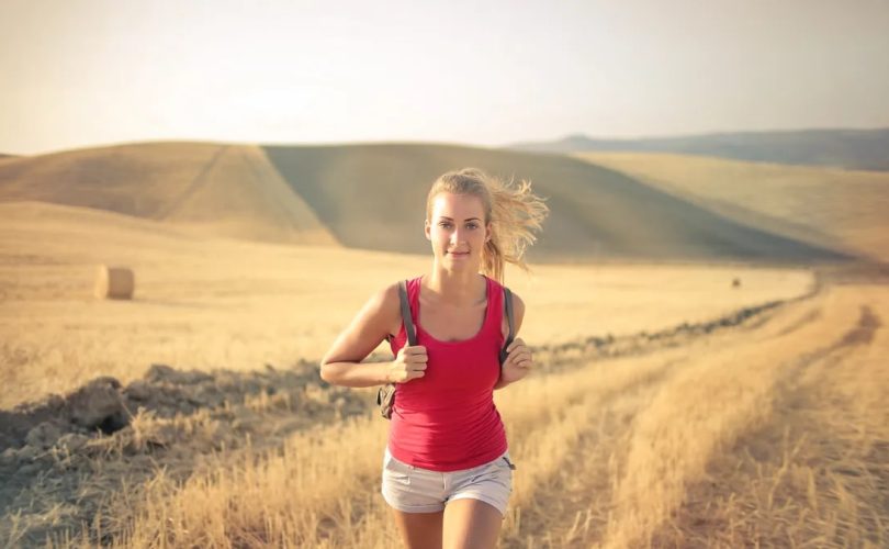 A woman jogging through vast, golden wheat fields under the summer sun, symbolizing freedom and adventure.